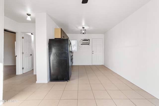 kitchen with black refrigerator, a wall mounted AC, and light tile patterned flooring