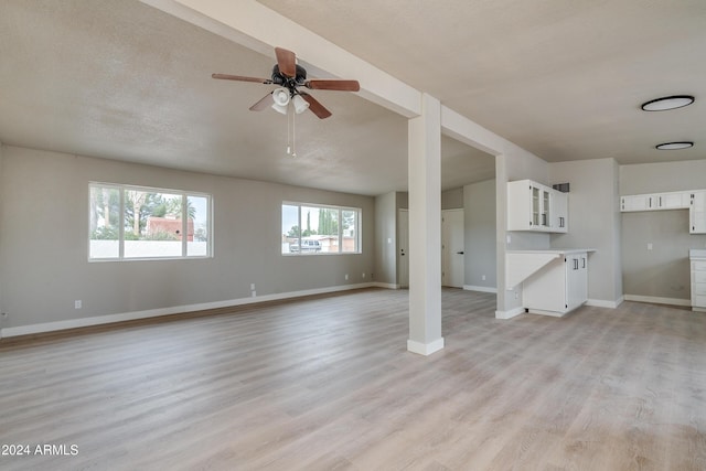 unfurnished living room featuring ceiling fan, light hardwood / wood-style floors, and a textured ceiling