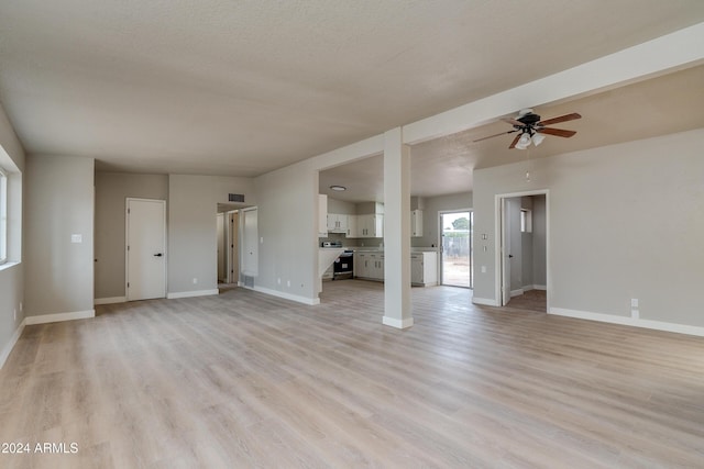 unfurnished living room with ceiling fan, light wood-type flooring, and a textured ceiling