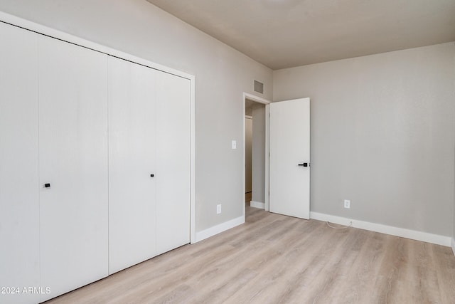 unfurnished bedroom featuring light wood-type flooring and a closet