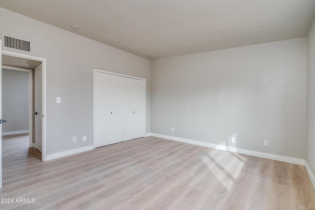 unfurnished bedroom with a closet and light hardwood / wood-style floors