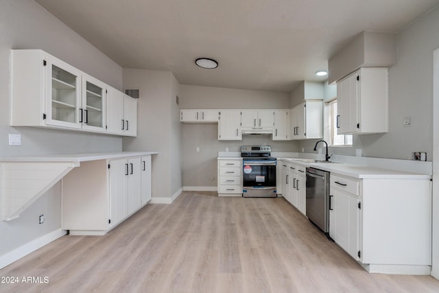 kitchen featuring white cabinets, sink, vaulted ceiling, light hardwood / wood-style flooring, and appliances with stainless steel finishes