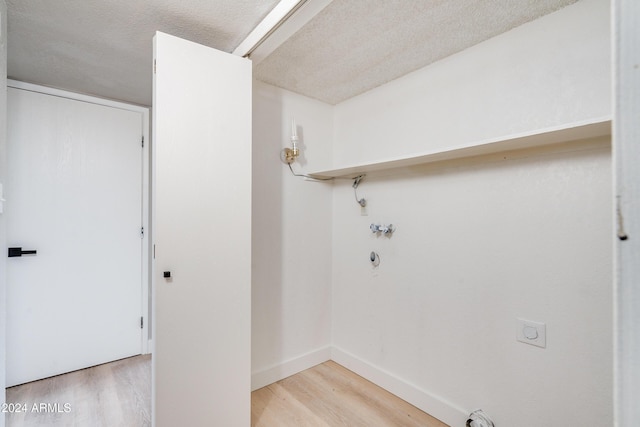 laundry area featuring hookup for an electric dryer, a textured ceiling, hookup for a gas dryer, and light hardwood / wood-style flooring