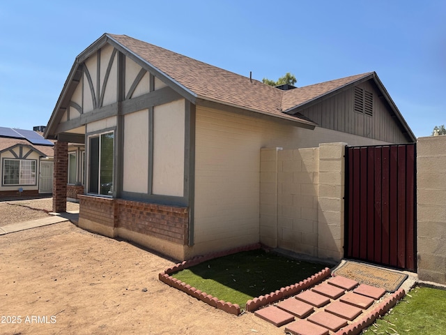 8520 W Palm Ln Unit 1054, Phoenix, AZ 85037 - view of property exterior with roof with shingles, brick siding, and a gate