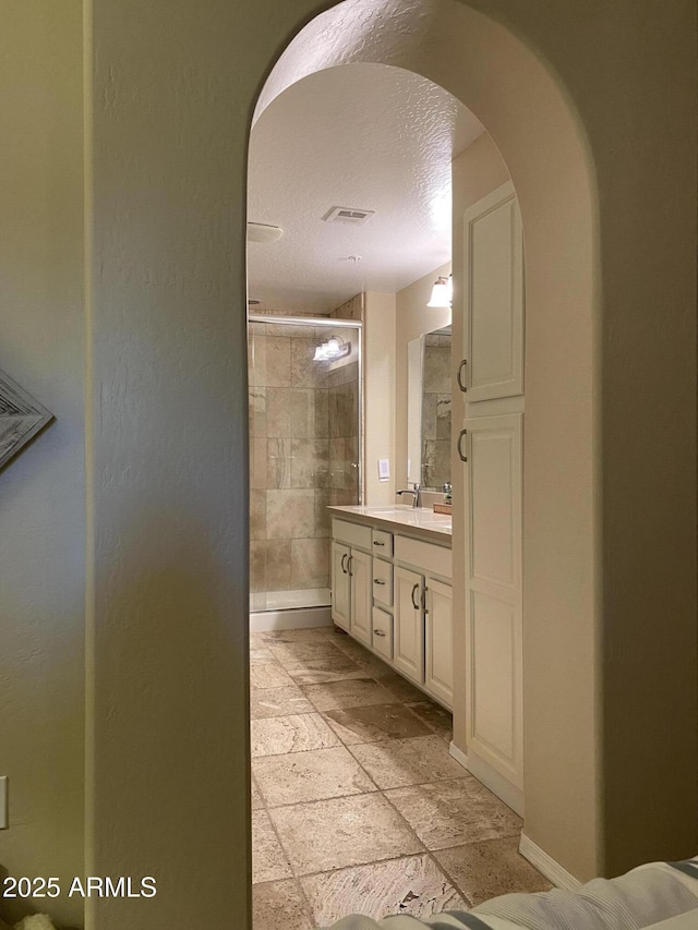 14575 W Mountain View Blvd Unit 711, Surprise, AZ 85374 - full bath featuring a shower stall, vanity, a textured ceiling, stone tile floors, and baseboards