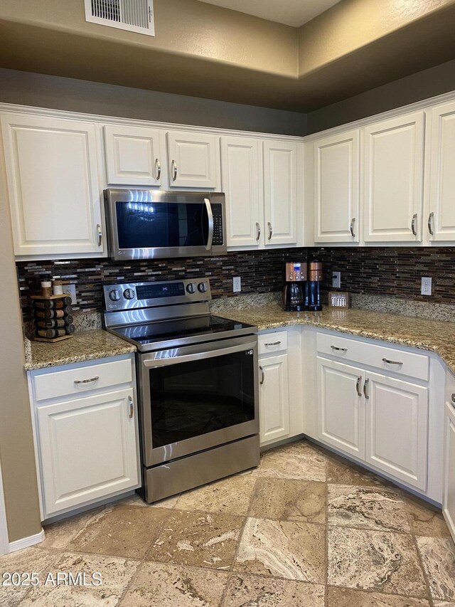 14575 W Mountain View Blvd Unit 711, Surprise, AZ 85374 - kitchen featuring stainless steel appliances, stone tile floors, decorative backsplash, and white cabinets
