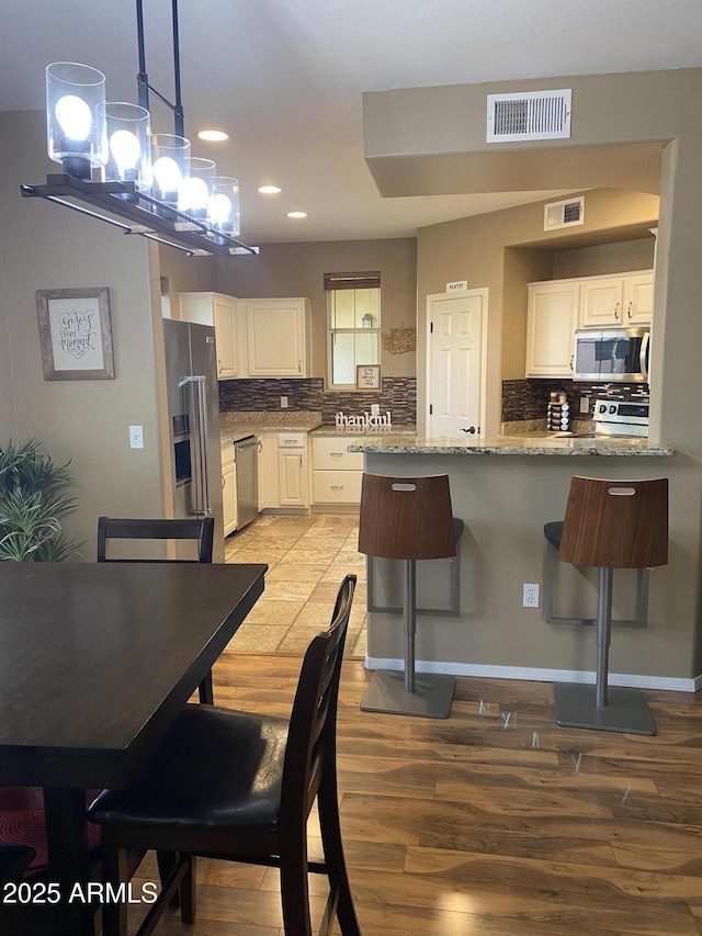 14575 W Mountain View Blvd Unit 711, Surprise, AZ 85374 - kitchen featuring appliances with stainless steel finishes, recessed lighting, light wood finished floors, a peninsula, and white cabinetry