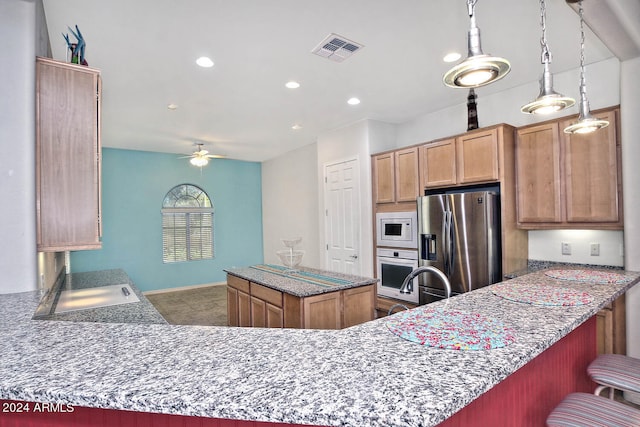 kitchen featuring kitchen peninsula, appliances with stainless steel finishes, ceiling fan, sink, and hanging light fixtures