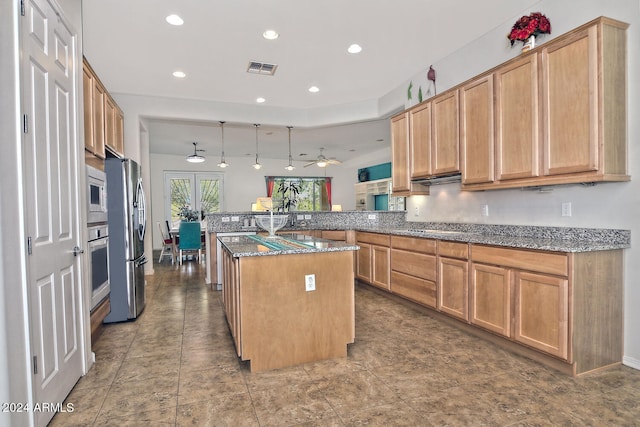 kitchen with dark stone counters, hanging light fixtures, appliances with stainless steel finishes, a kitchen island, and kitchen peninsula