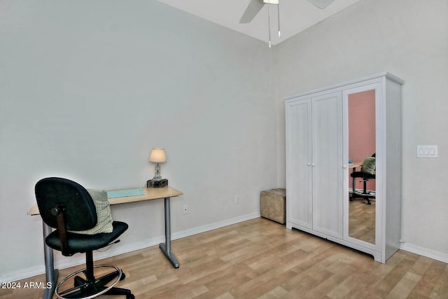 home office featuring ceiling fan, light hardwood / wood-style flooring, and a towering ceiling