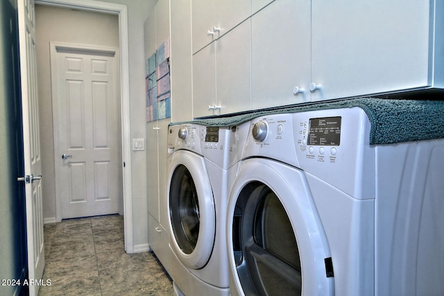 clothes washing area with washing machine and dryer and cabinets