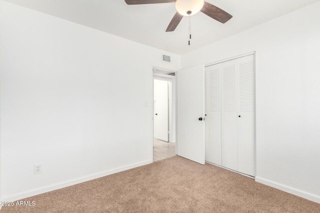 unfurnished bedroom with a closet, light colored carpet, visible vents, a ceiling fan, and baseboards