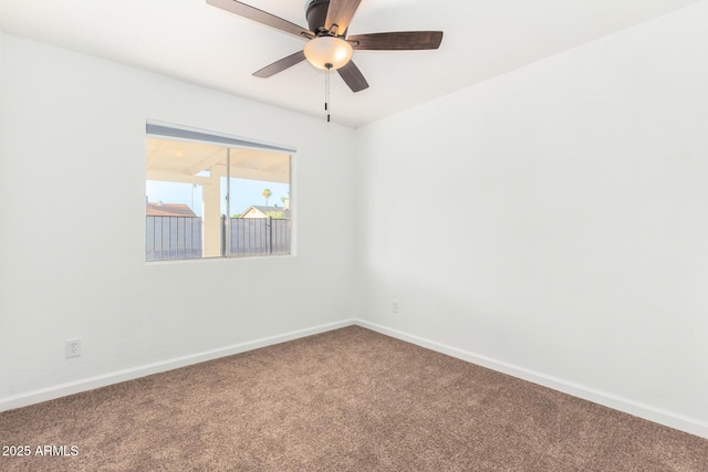 empty room with carpet floors, a ceiling fan, and baseboards