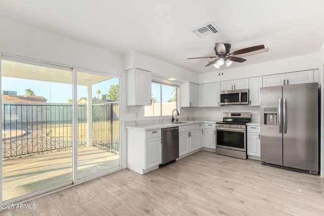 kitchen featuring stainless steel appliances, visible vents, light wood-style floors, white cabinetry, and light countertops