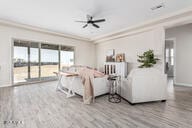 living room with wood-type flooring, ceiling fan, and ornamental molding