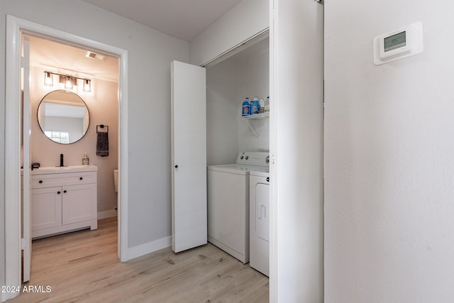 clothes washing area with independent washer and dryer and light hardwood / wood-style floors