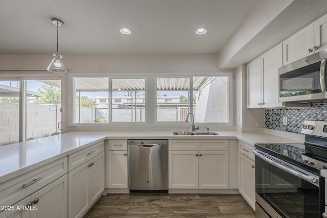 kitchen featuring stainless steel appliances, tasteful backsplash, light countertops, white cabinets, and a sink