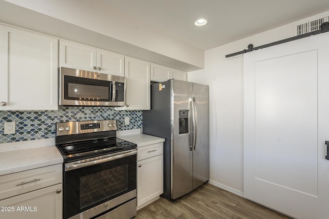 kitchen featuring tasteful backsplash, a barn door, stainless steel appliances, and light countertops