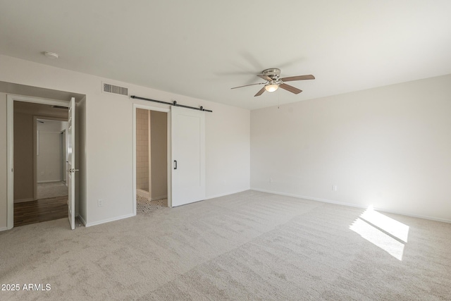 unfurnished bedroom featuring a barn door, light colored carpet, a ceiling fan, baseboards, and visible vents