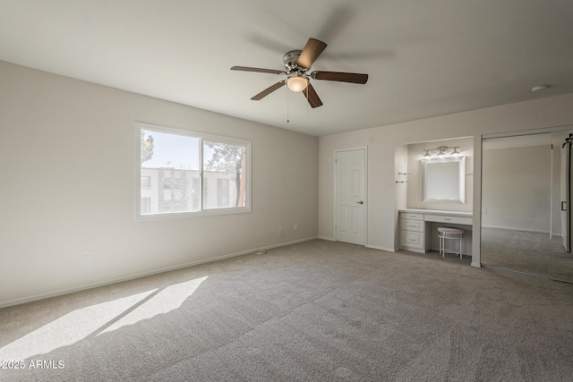 unfurnished bedroom with two closets, baseboards, a ceiling fan, and carpet flooring