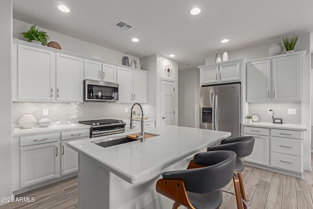 kitchen featuring a kitchen island with sink, appliances with stainless steel finishes, sink, and white cabinets