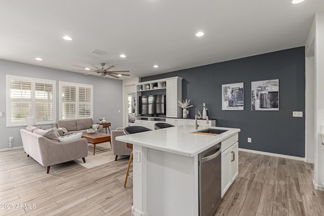 kitchen with a kitchen island with sink, dishwasher, sink, and white cabinets