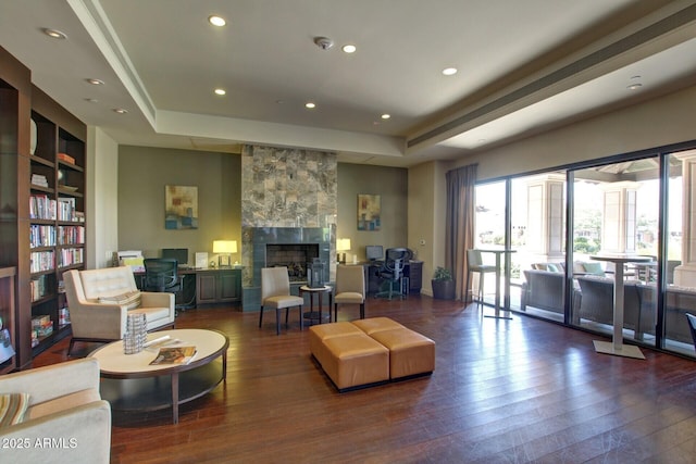 living room with hardwood / wood-style flooring, a fireplace, and a raised ceiling