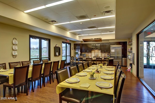 dining area featuring french doors, dark wood-type flooring, and a drop ceiling