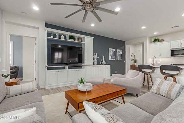 living room with ceiling fan and light wood-type flooring