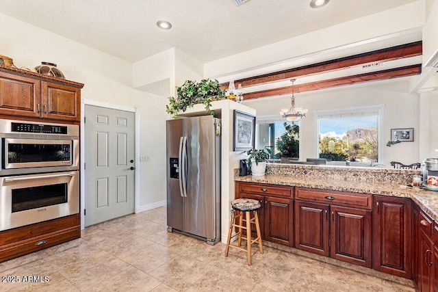 kitchen with an inviting chandelier, recessed lighting, light stone counters, appliances with stainless steel finishes, and hanging light fixtures