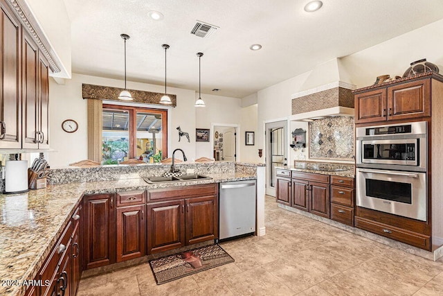 kitchen with a sink, stainless steel appliances, a peninsula, visible vents, and custom exhaust hood