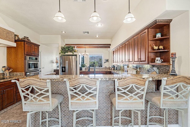 kitchen featuring open shelves, a kitchen bar, light stone counters, a sink, and stainless steel appliances