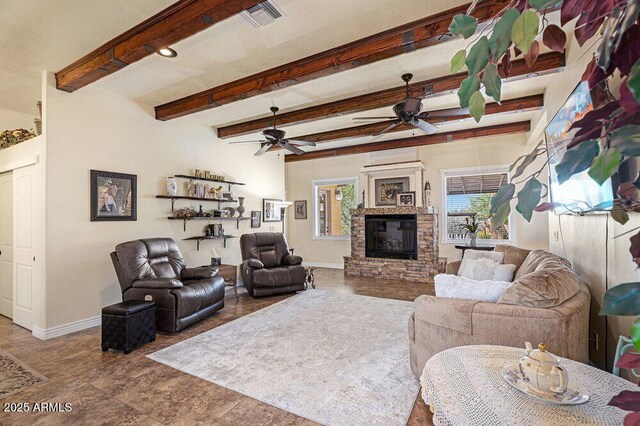 living room with ceiling fan, a stone fireplace, visible vents, beam ceiling, and baseboards