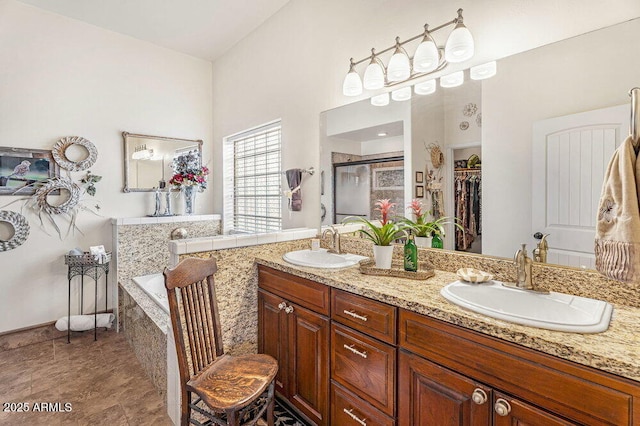 full bathroom with double vanity, a shower stall, a sink, and a garden tub