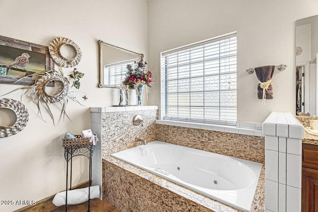 full bath with a tub with jets, a wealth of natural light, and vanity