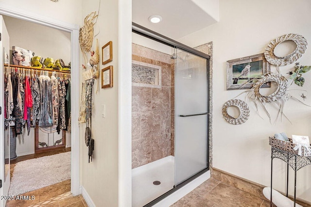 full bathroom featuring baseboards, a stall shower, tile patterned floors, and a spacious closet