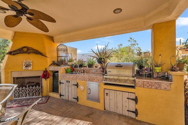 view of patio / terrace featuring a sink, an outdoor kitchen, exterior fireplace, and a grill