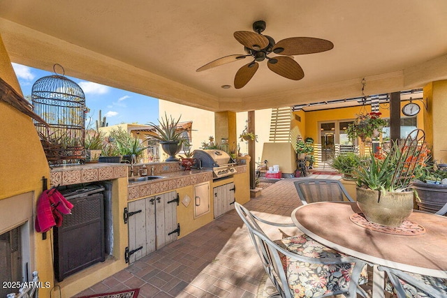 view of patio with a sink, outdoor dining area, area for grilling, a ceiling fan, and exterior kitchen
