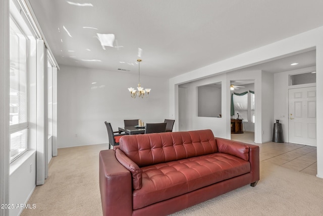 carpeted living room featuring ceiling fan with notable chandelier