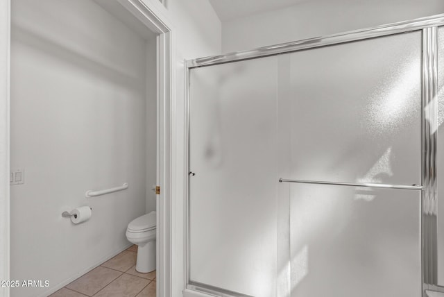 bathroom featuring tile patterned floors, toilet, and an enclosed shower