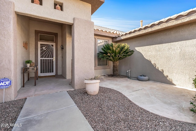 view of exterior entry with a patio