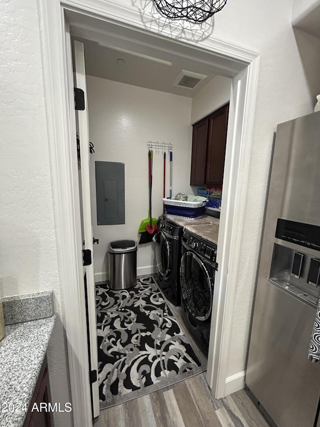 laundry area featuring cabinets, independent washer and dryer, electric panel, and light hardwood / wood-style flooring