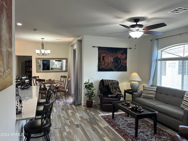 living room with hardwood / wood-style floors, ceiling fan with notable chandelier, and crown molding