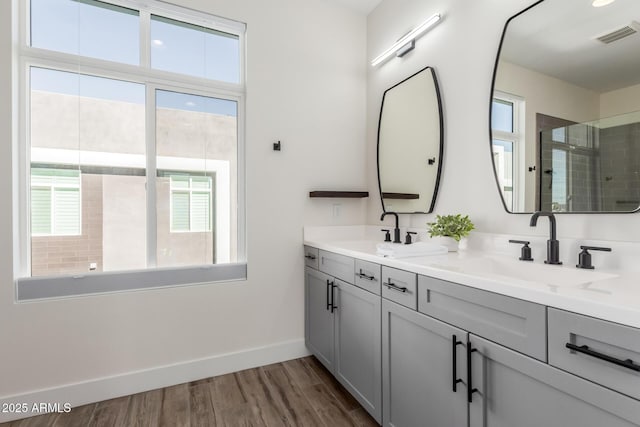 bathroom with hardwood / wood-style flooring, plenty of natural light, vanity, and a shower with door