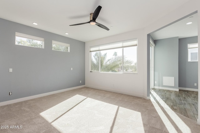 spare room with light carpet, ceiling fan, and a wealth of natural light