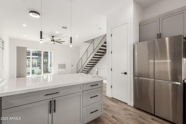 kitchen featuring ceiling fan, light hardwood / wood-style flooring, stainless steel fridge, and gray cabinets