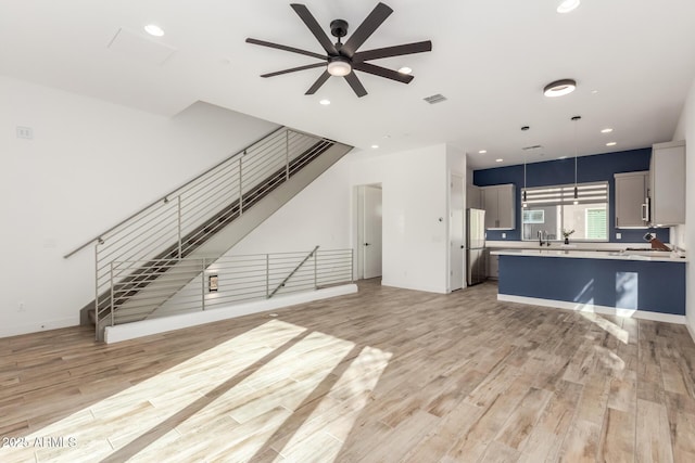 living room featuring light wood-type flooring, ceiling fan, and sink