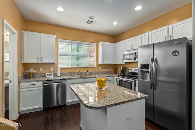 2031 N 77th Ln, Phoenix, AZ 85035 - kitchen featuring appliances with stainless steel finishes, a sink, light stone countertops, white cabinetry, and a kitchen island