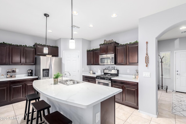 kitchen with appliances with stainless steel finishes, pendant lighting, sink, a kitchen island with sink, and dark brown cabinetry