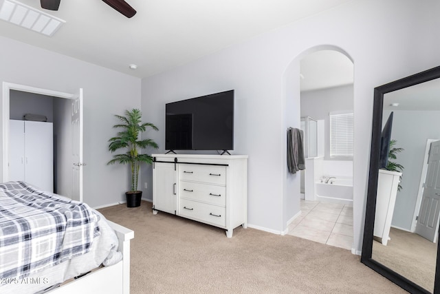 bedroom featuring light carpet, ceiling fan, and ensuite bathroom